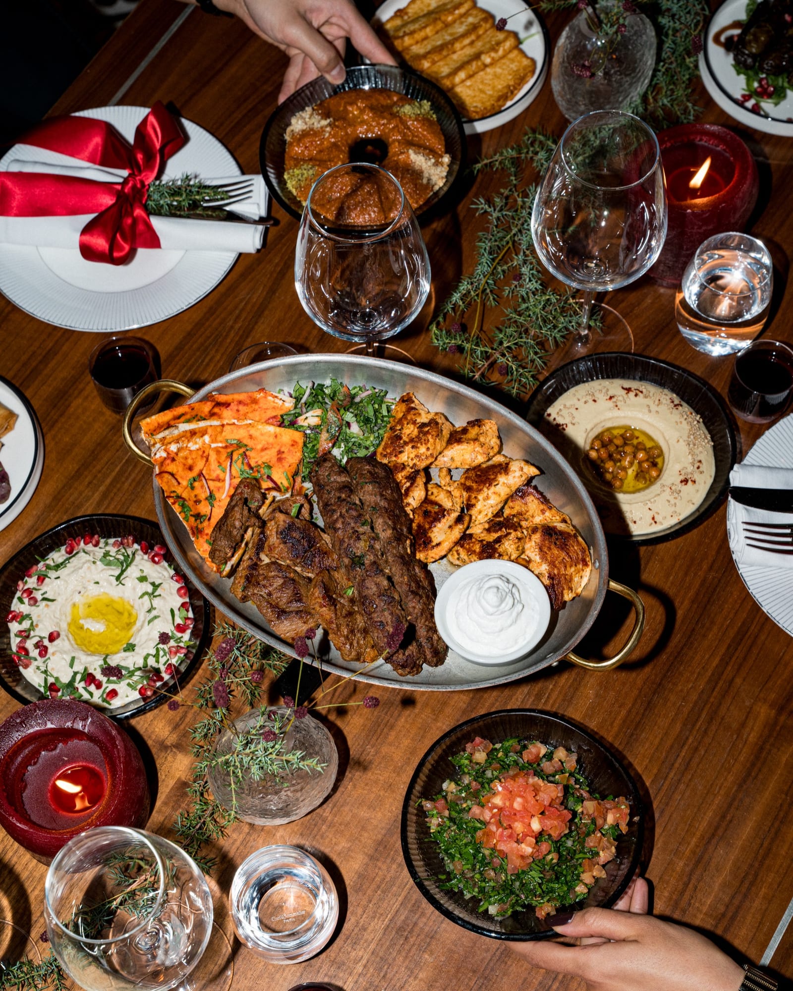 Festdukat bord med grillfat, hoummos, baba ghanouj och tabbouleh vid levande ljus